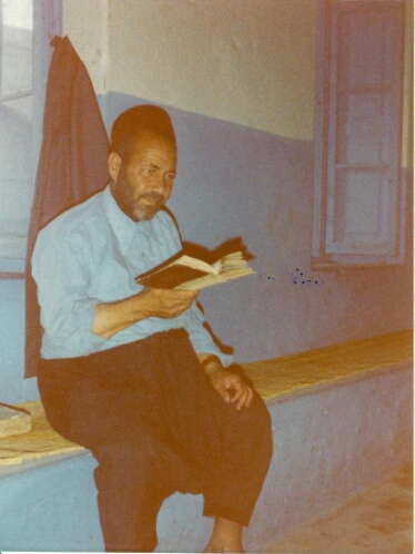 Dans la synagogue de la Ghriba, un "battlan", un "pensionnaire" de la communauté, assis sur un banc, un livre ouvert à la main